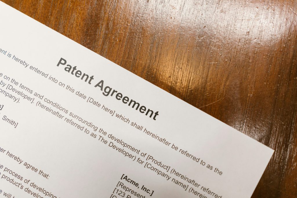 pexels-photo-7841818-7841818 Detailed close-up of a patent agreement document on a polished wooden table.